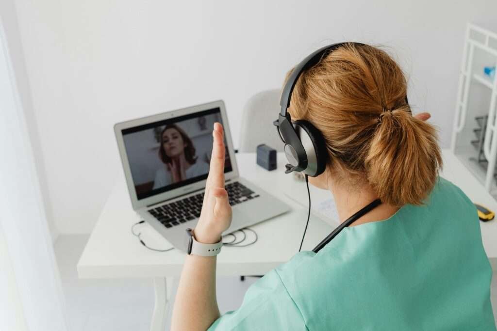 A female doctor engaged in a video call consultation with a patient on a laptop.