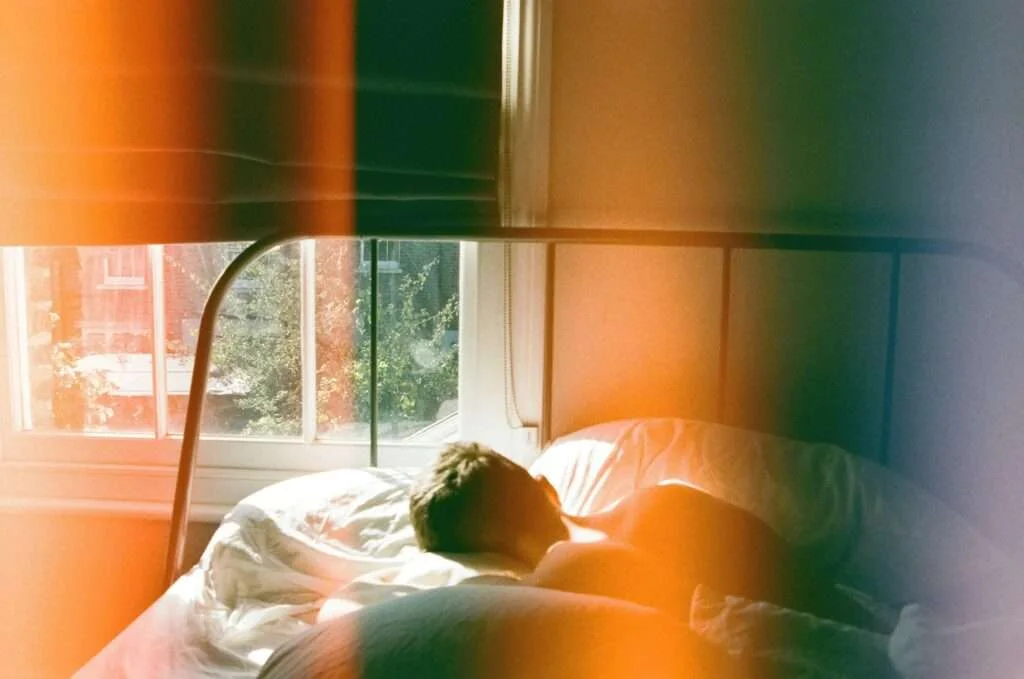 A man peacefully sleeping in a London bedroom, bathed in soft morning light.